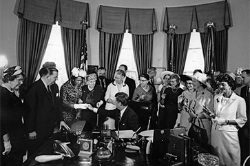 Black-and-white photo of President John F. Kennedy signing the Equal Pay Act