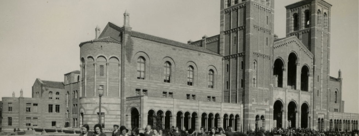 A black and white photograph taken in the 1930s depicting students walking across the Royce Hall Terrace, books in hand.