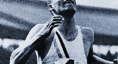 A black and white photograph depicting James "Jimmy" LuValle in a sleeveless running shirt with the number "4" pinned to the front.