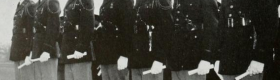 A black and white photograph of seven men in military dress blues standing shoulder to shoulder.