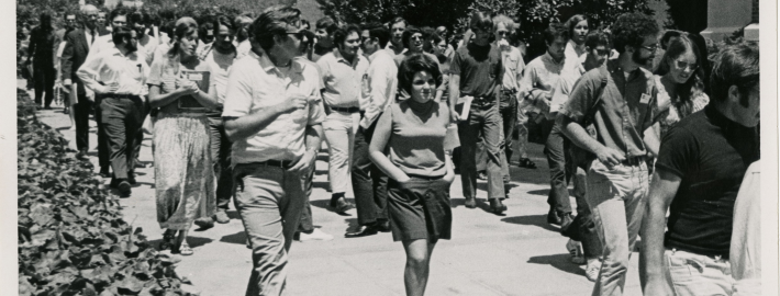 A black and white photograph of students walking through the UCLA campus.