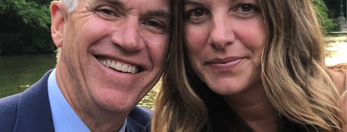 A head and shoulders of (from left to right) Matthew C. Harris and Jennifer Harris, an alumnus, with trees and flowing water in the background.