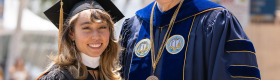 From left to right, gymnast and alumnus Katelyn Ohashi and Chancellor Gene Block in graduation regalia standing outside.