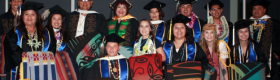 Students and faculty members in graduation regalia attending an American Indian Studies graduation celebration.