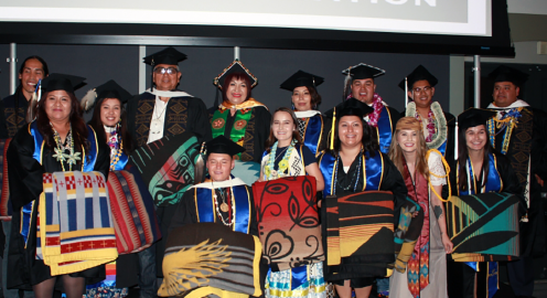 Students and faculty members in graduation regalia attending an American Indian Studies graduation celebration.