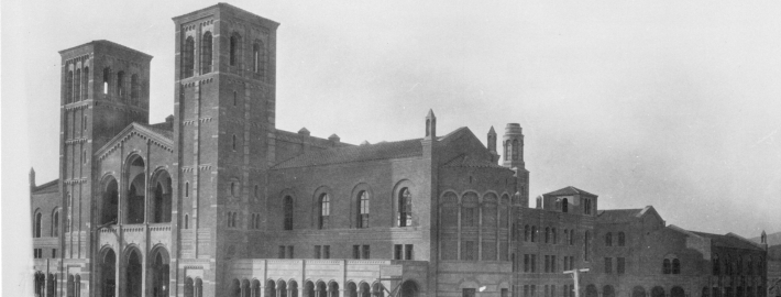 A black and white photograph of cars from the 1920s and building materials surrounding Royce Hall.