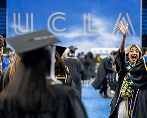 Students celebrate commencement with UCLA sign in background