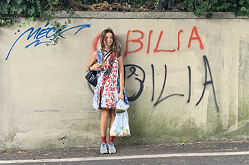 Elya Aboutboul-Bilia stands against a concrete wall.