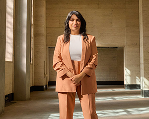 Saba Waheed at the historic Trust Building, the site of her office in the new UCLA Downtown campus, wearing a salmon colored suit.