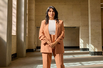 Saba Waheed at the historic Trust Building, the site of her office in the new UCLA Downtown campus, wearing a salmon colored suit.