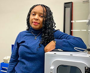 Professor Alvine Kamaha standing in front of instrumentation in her laboratory