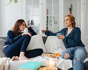 Two people speaking while seated on a couch.