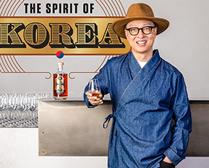 Bryan Do leaning against a bar top with an illustration in the background that reads: The Spirit of Korea.