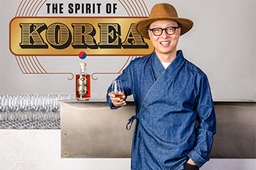 Bryan Do leaning against a bar top with an illustration in the background that reads: The Spirit of Korea.