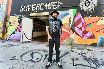 Erick Zerecero, dressed in black, standing in front of Superchief sign