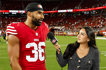 Lindsey Pallares, right, interviewing Curtis Robinson on football field