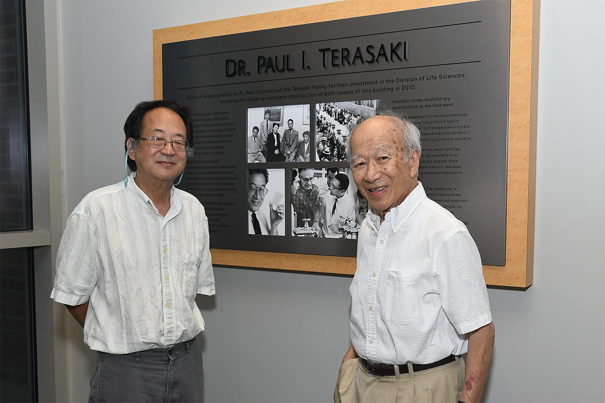 Mark Terasaki (left) and Richard Terasaki standing in front of a large plaque dedicated to the late Dr. Paul I. Terasaki.