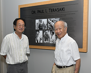 Mark Terasaki (left) and Richard Terasaki standing in front of a large plaque dedicated to the late Dr. Paul I. Terasaki.