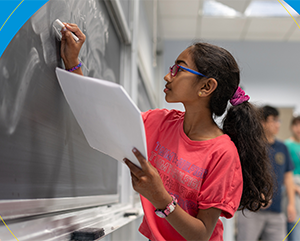 A young female student drawing math equations on a chalk board.