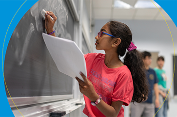 A young female student drawing math equations on a chalk board.