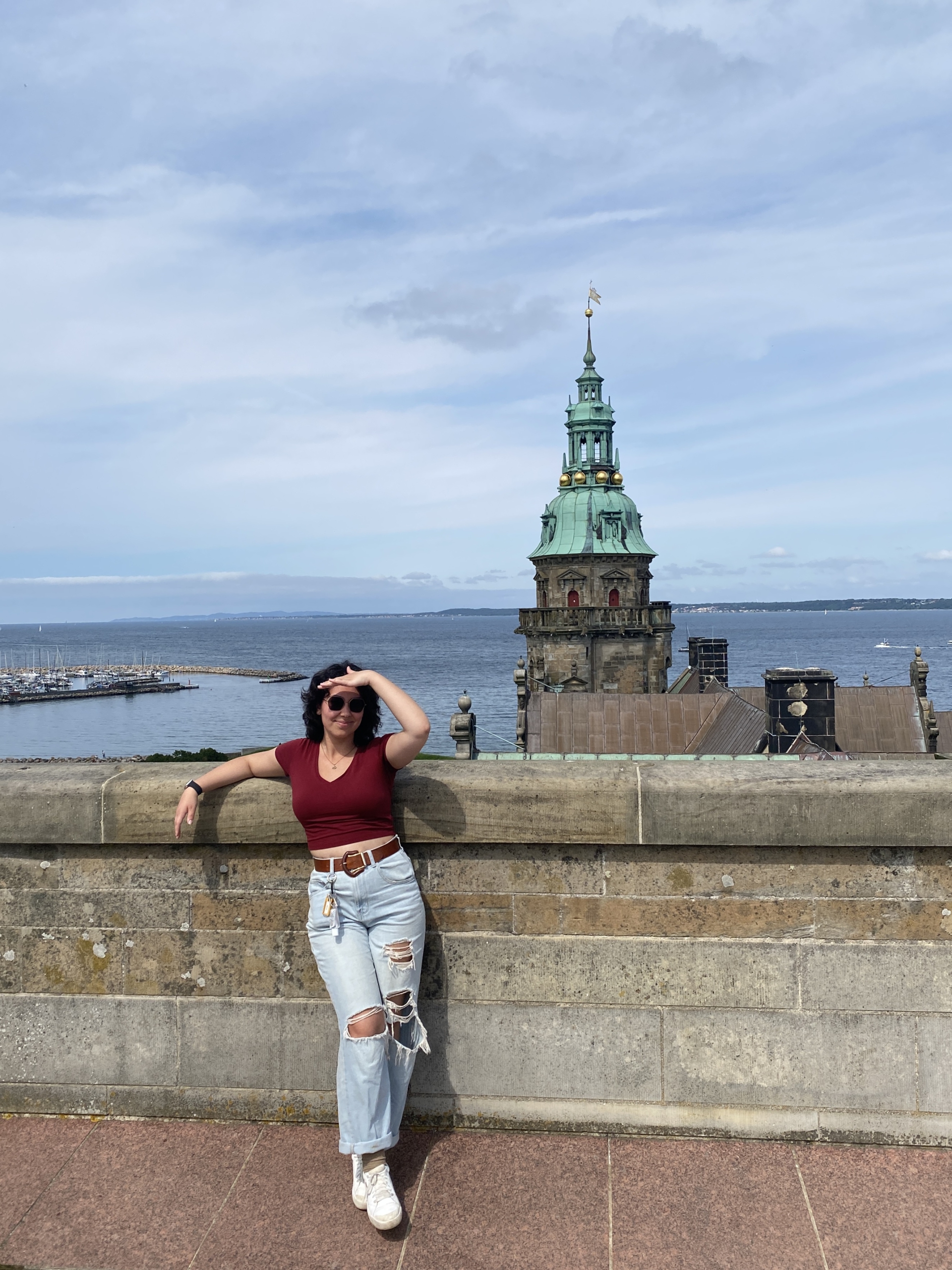 Gabrielle Lopez standing on a bridge in Copenhagen, shielding her eyes in the sun.