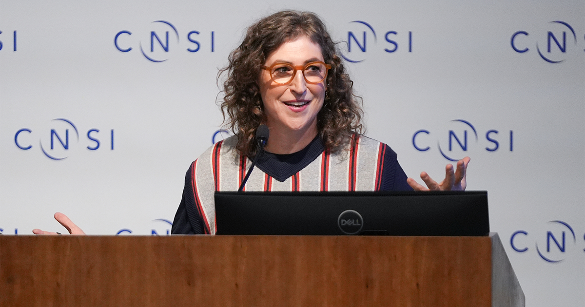 Mayim Bialik speaking at a podium. 