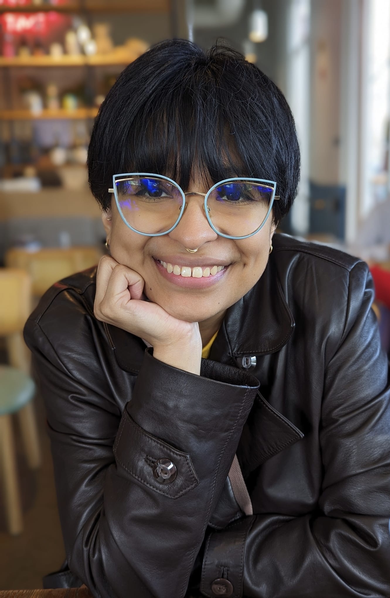 Nancy Alicia Martínez in a black leather jacket and turquoise-rimmed cat's-eye glasses.