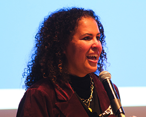 Safiya Noble speaks into a microphone at her installation ceremony as the David O. Sears Presidential Chair in Social Sciences.