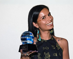 Nina Gualinga smiling and holding trophy