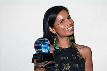 Nina Gualinga smiling and holding trophy