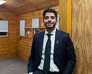 Mohammed Alharthi in suit and tie standing inside a wood-paneled room