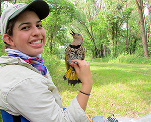 Stepfanie Aguillon in an outdoor setting with a small bird perched on her hand