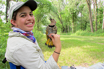 Stepfanie Aguillon in an outdoor setting with a small bird perched on her hand