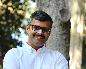 Tejas Parasher in a white shirt against a blurry outdoor setting