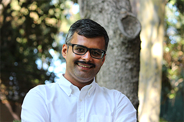 Tejas Parasher in a white shirt against a blurry outdoor setting