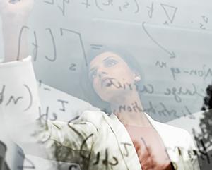 Pri Narang writing math equations on a glass whiteboard.