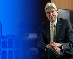 UCLA Chancellor Dr. Julio Frenk seated in front of Royce Hall with partial blue tinted treatment