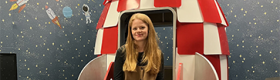 Meg Cychosz sitting in a model rocket ship in her research lab