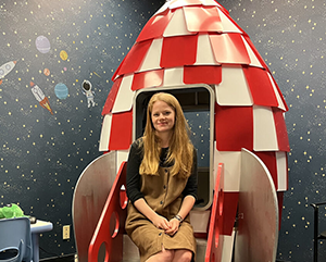 Meg Cychosz sitting in a model rocket ship in her research lab