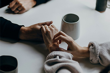 Two people hold hands atop a table