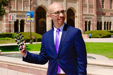 Maher El-Kady holding a molecule diagram as he stands in front of the Shapiro Fountain.