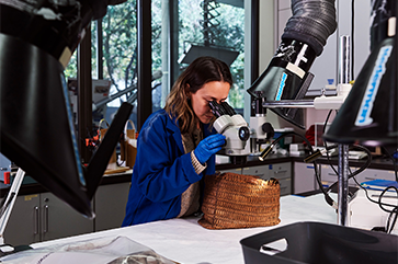 First-year conservation student Fernanda Baxter examines a basket.