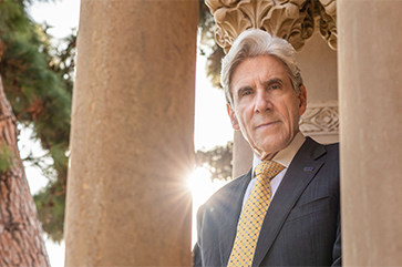 Julio Frenk standing in front of stone columns.