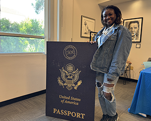 Student Títílọpẹ́ Olotu stands with an oversized U.S. passport