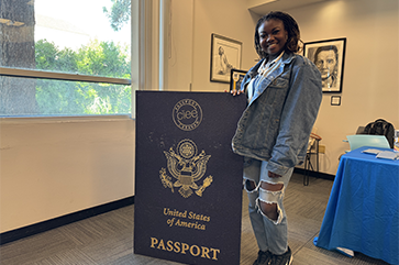 Student Títílọpẹ́ Olotu stands with an oversized U.S. passport