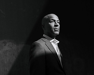 A black and white photograph of Paul Taylor with a spotlight placed on his head and shoulders.