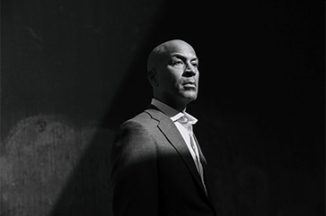 A black and white photograph of Paul Taylor with a spotlight placed on his head and shoulders.