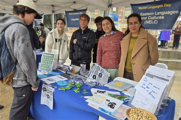 Volunteers with a visitor at the Near Eastern Languages and Cultures table at World Languages Day.