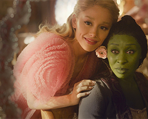 “Wicked” actors Ariana Grande and Cynthia Erivo look in a mirror in one of the film's scenes