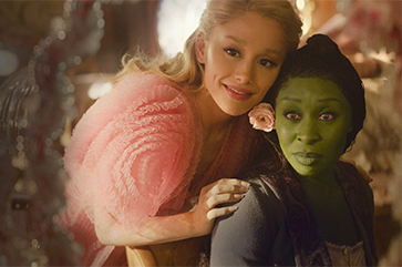 “Wicked” actors Ariana Grande and Cynthia Erivo look in a mirror in one of the film's scenes